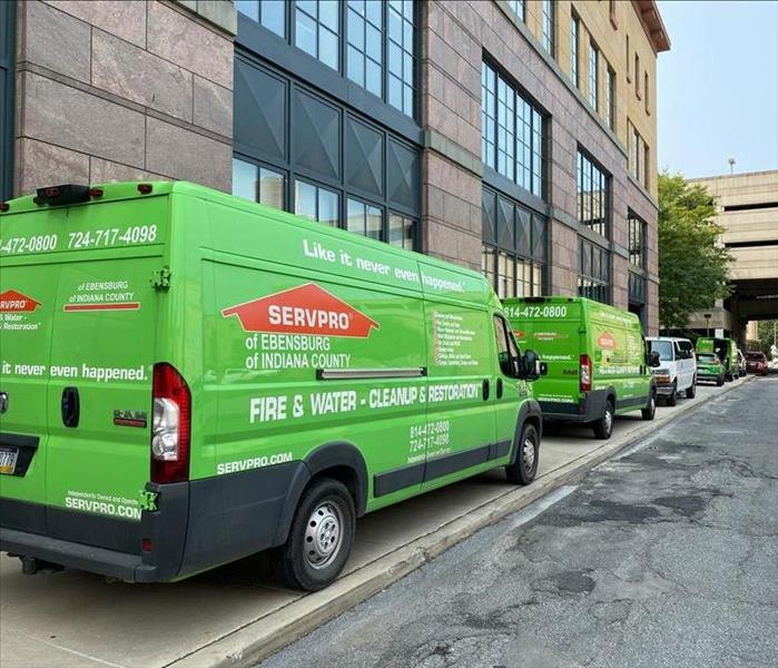 Line of SERVPRO vehicles parked on the street responding to a large loss downtown